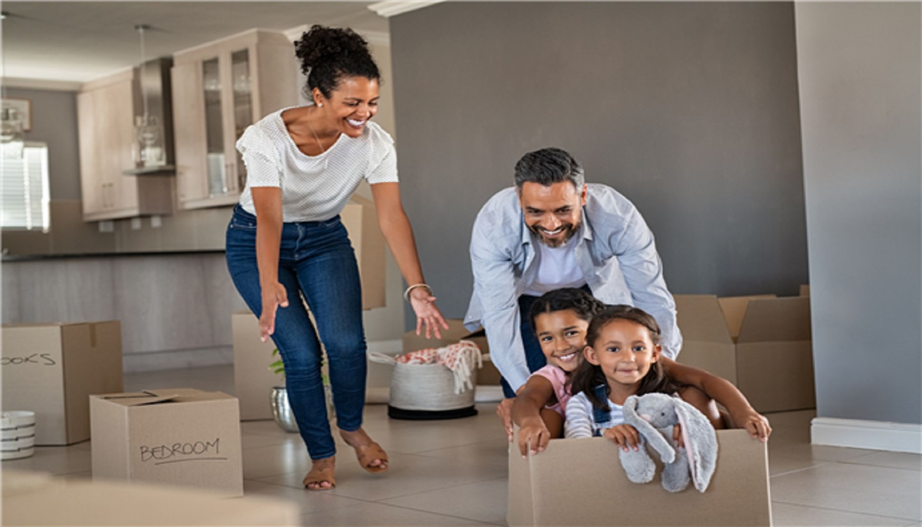 Family moving into their new house, dad pushing kids in box